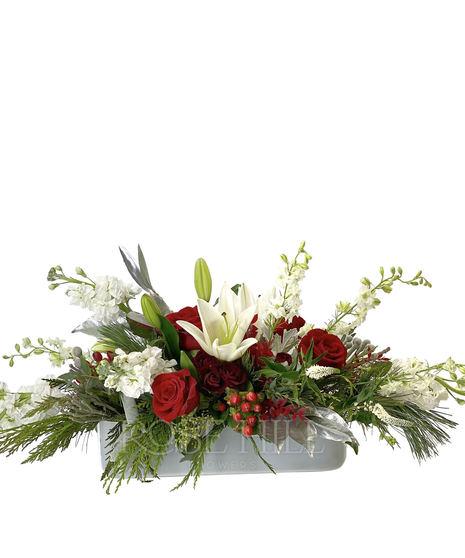 Stunning holiday centerpiece with red roses, other white premium flowers with winter greens and berry accents.