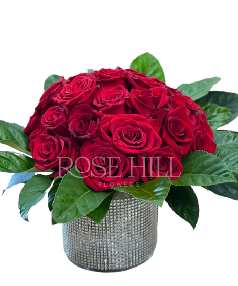 Vase covered in sequin bling filled with bright roses.